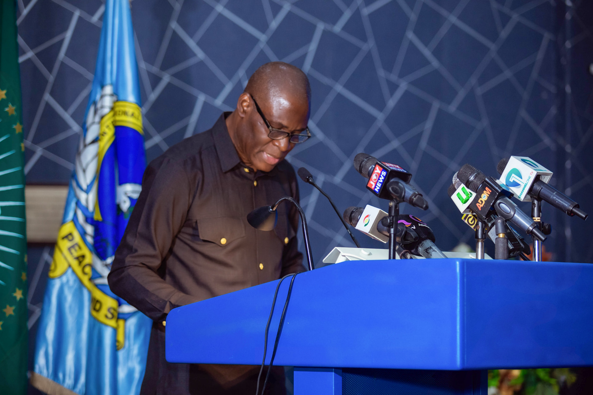 A speaker addressing the 2024 Dialogue, with press microphones from Ghana's major media houses at the podium
