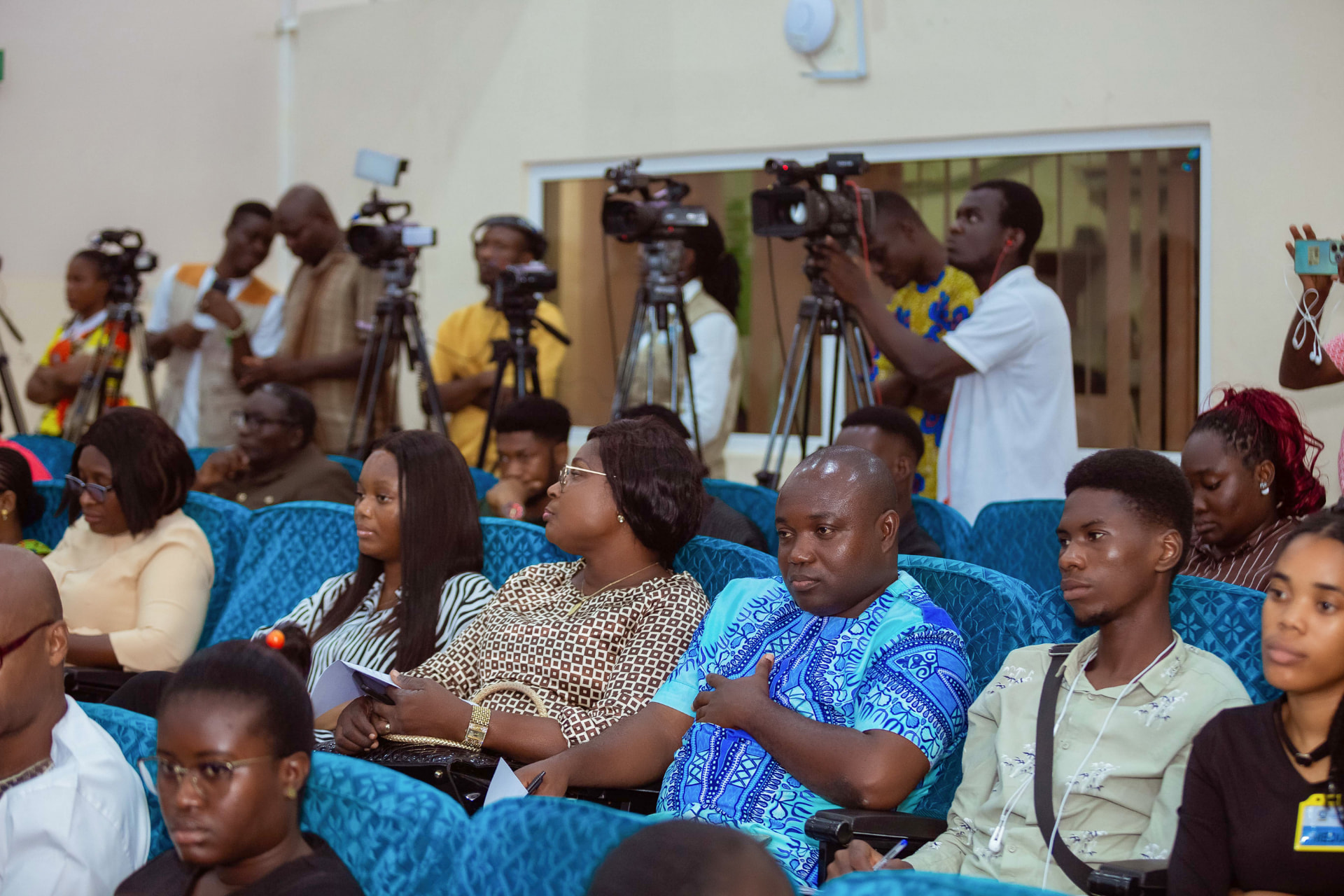 The audience seated as television crews record from the back of the hall