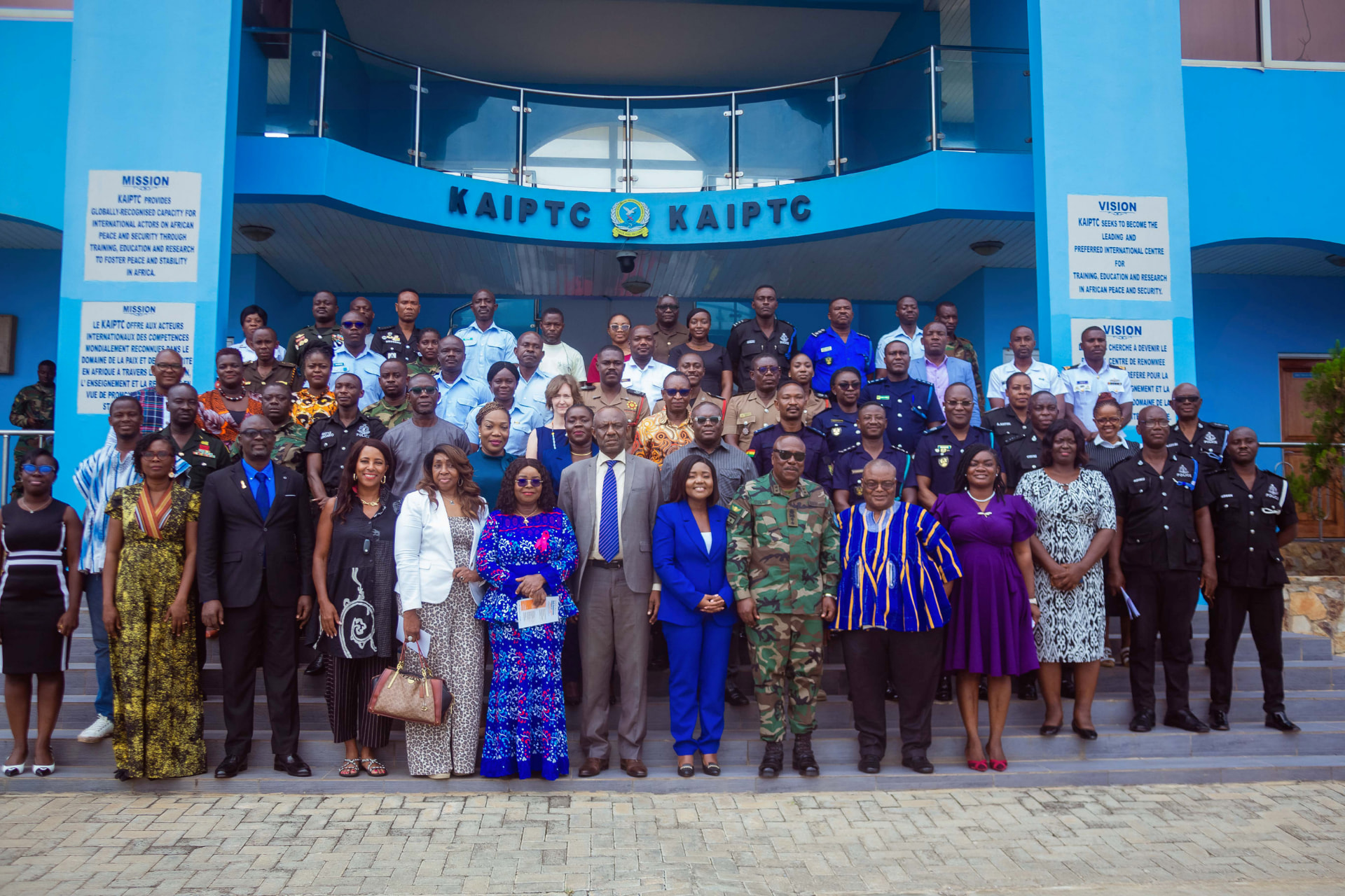 Delegates, military officers and police officers pose together on the steps outside the KAIPTC building