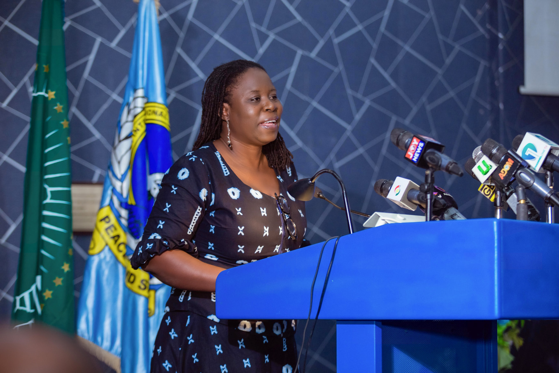 A delegate addressing the Dialogue from the podium, beside the African Union and KAIPTC flags