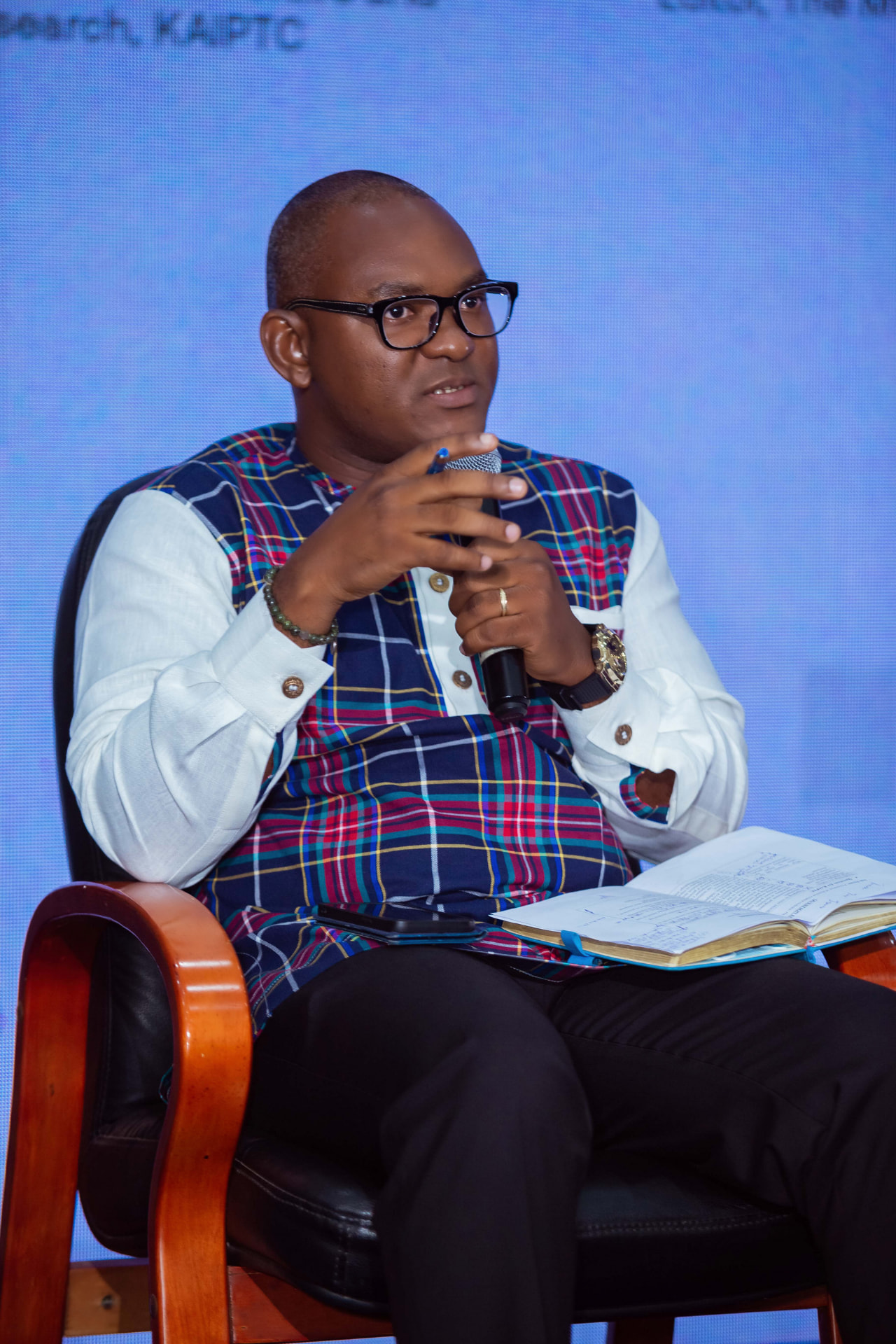A panellist speaking during the discussion, his notes resting on his lap