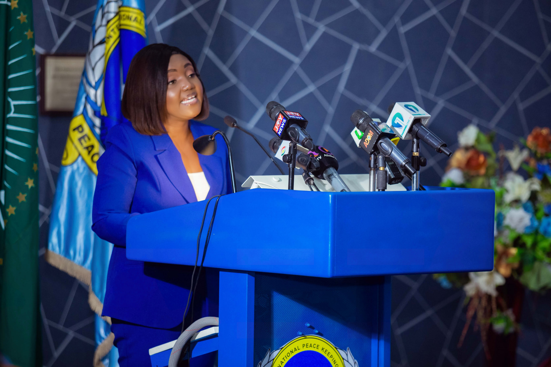 Princess Sekyere-Bih speaking at the podium, with microphones from Joy News, Adom and Channel One TV